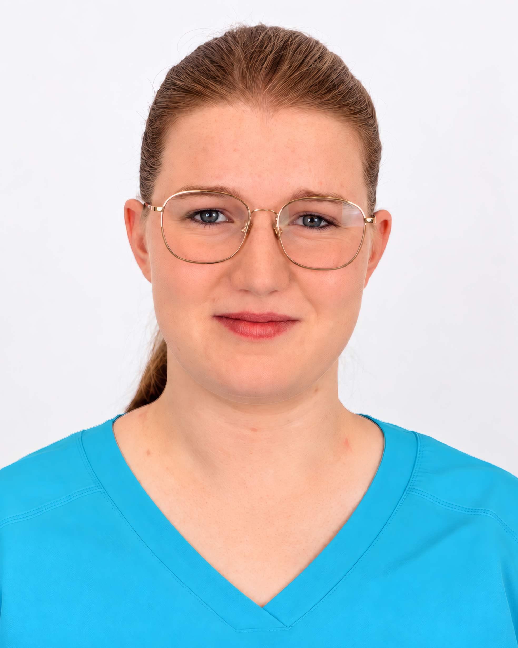 Portrait einer Frau mit zurückgebundenen rotblonden Haaren und goldfarbener Metallbrille, die freundlich lächelt. Sie trägt ein türkisfarbenes Kasack-Oberteil mit V-Ausschnitt vor einem hellen, neutralen Hintergrund.